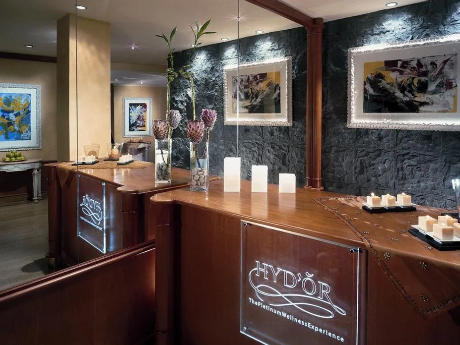 Reception della spa con bancone in legno, candele e opere d'arte alle pareti