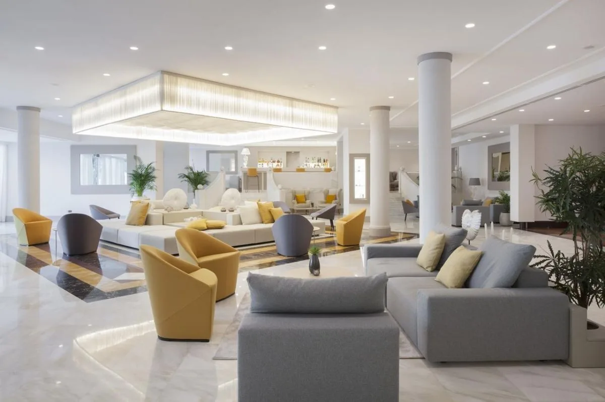 Ampia hall dell'hotel con poltrone gialle e grigie e pavimento in marmo lucido