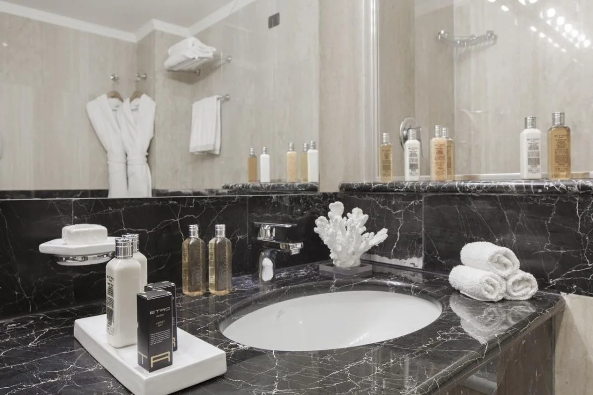 Bagno elegante in marmo nero con lavabo, kit cortesia e accappatoi