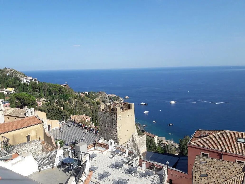Panorama sul mare blu e la costa di Taormina con torre antica e barche