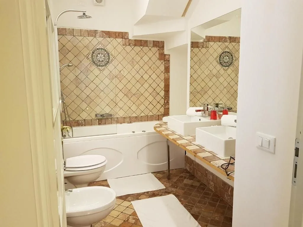 Bagno con vasca idromassaggio, doppio lavabo e piastrelle a mosaico beige