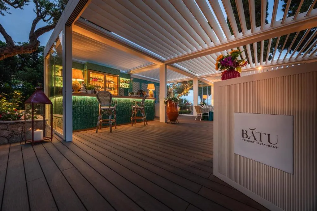 Ingresso del ristorante gourmet Batu con bar esterno e pavimentazione in legno di sera